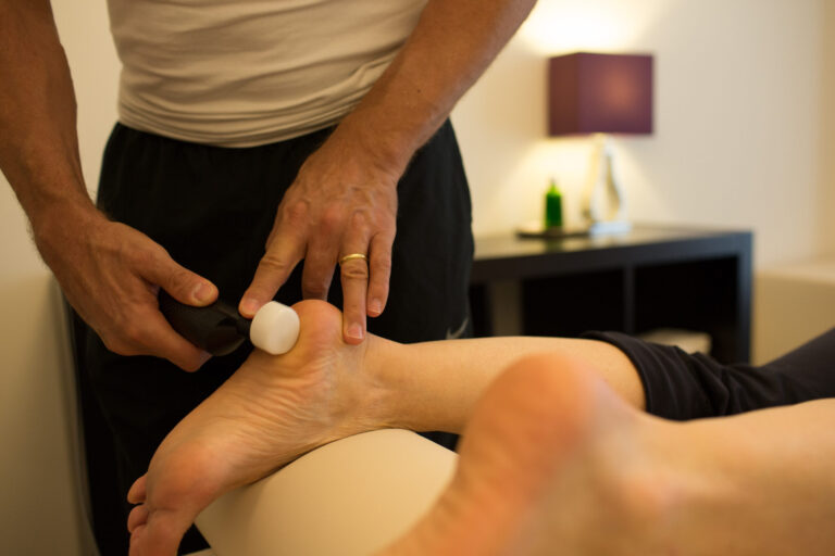 A therapist treats a client's foot with a matrix device.