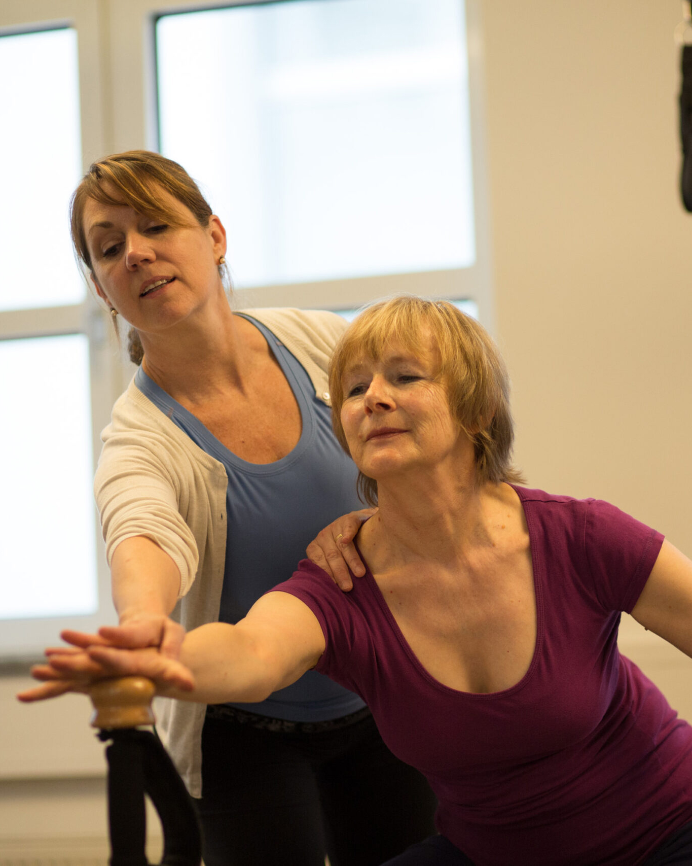 A trainer supports a client's arm position during an exercise on the Gyrotonic machine.