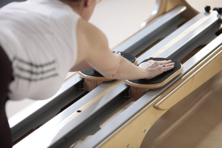 Nahaufnahme einer Hand auf den Griffplatten des Gyrotonic-Geräts