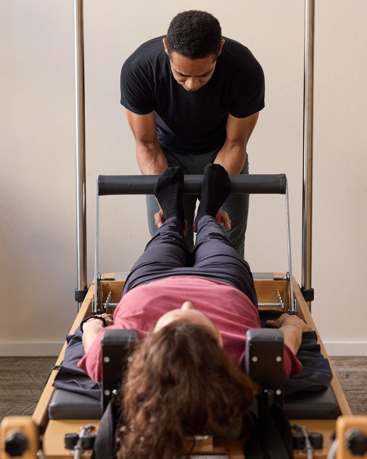 Trainer unterstützt Klientin auf dem Pilates Reformer Cadillac – Übung im Rahmen der Skoliose-Therapie