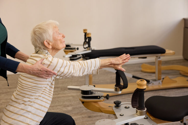 An older female client exercises on the Gyrotonic machine with her arm extended.