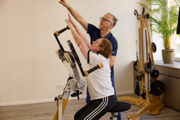 A trainer assists a client with a stretching exercise on the Gyrotonic machine.
