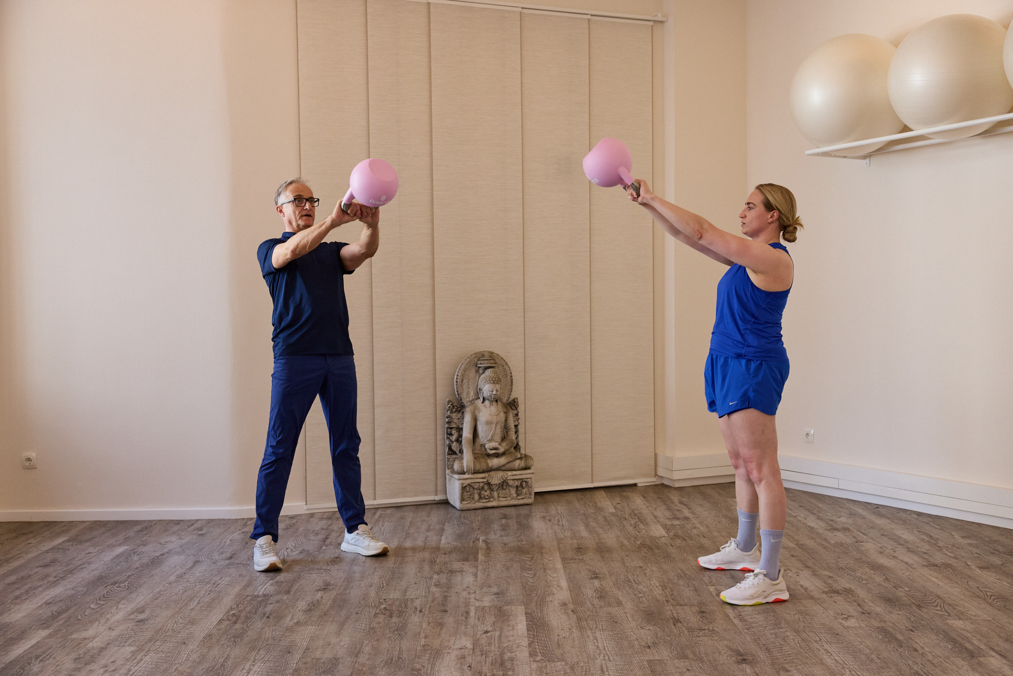 Trainer und Klientin trainieren mit Kettlebells im Kursraum