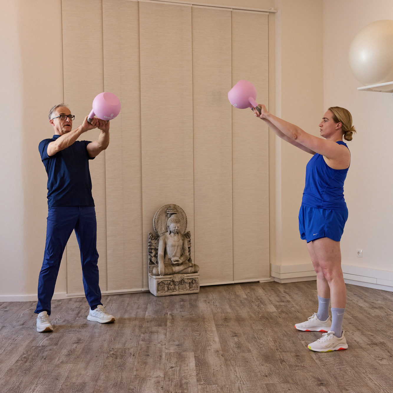 Trainer und Klientin trainieren gemeinsam mit Kettlebells im Studio – individuelles Präventionstraining