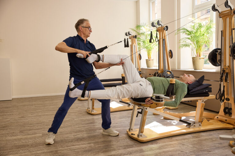 A trainer guides the leg of a client lying on the Gyrotonic machine.
