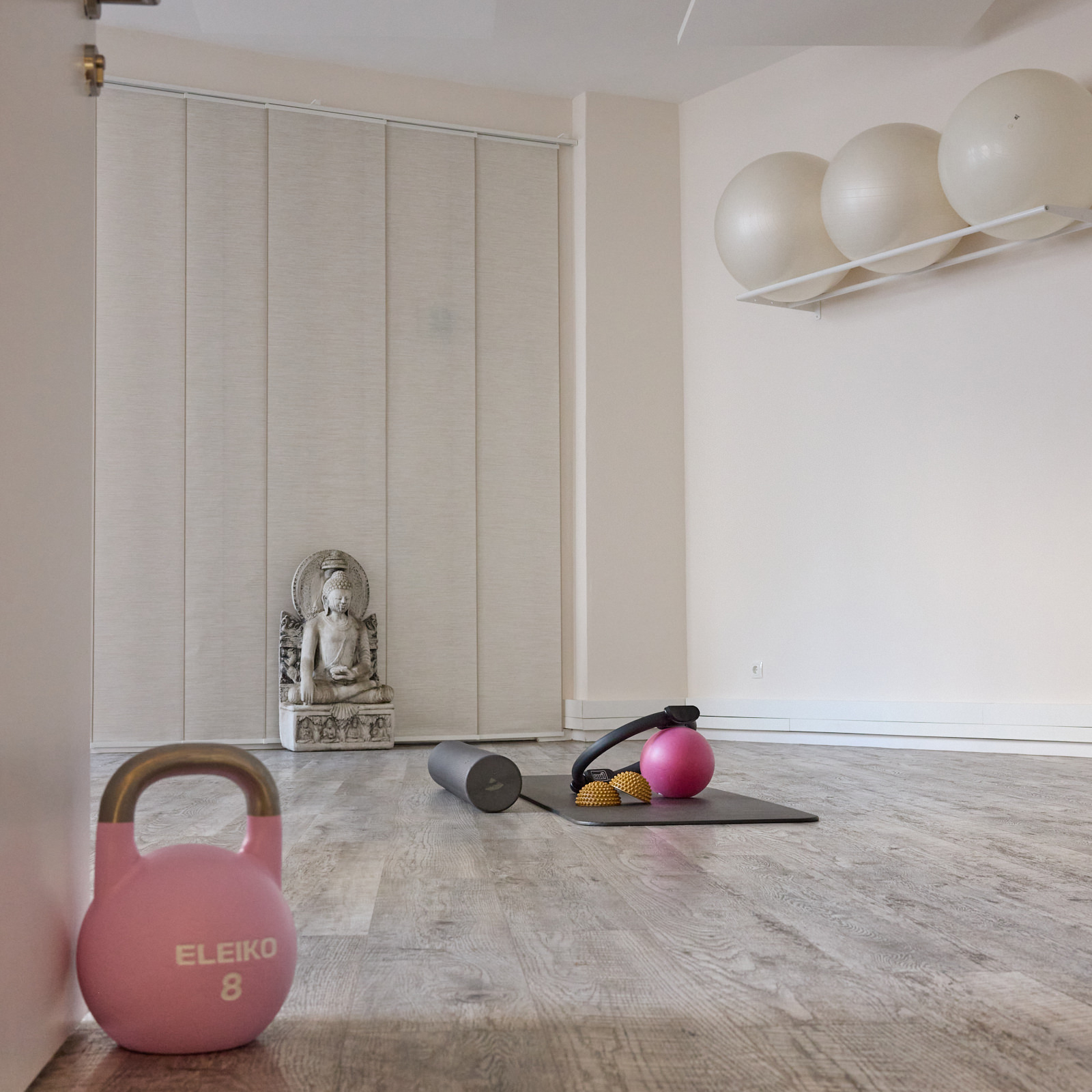 Übungsraum mit Kettlebell, Yogamatte, Faszienrolle und Buddha-Statue