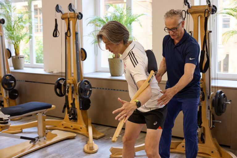 Trainer correcting a client's golf movement on the Gyrotonic machine.