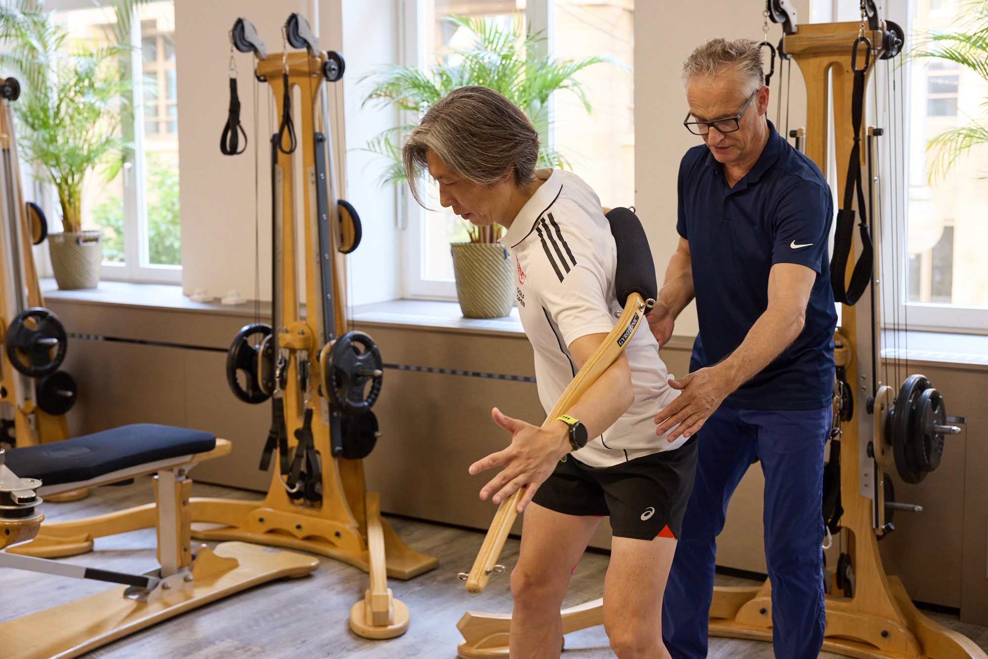 Trainer korrigiert die Golfbewegung eines Klienten am Gyrotonic-Gerät