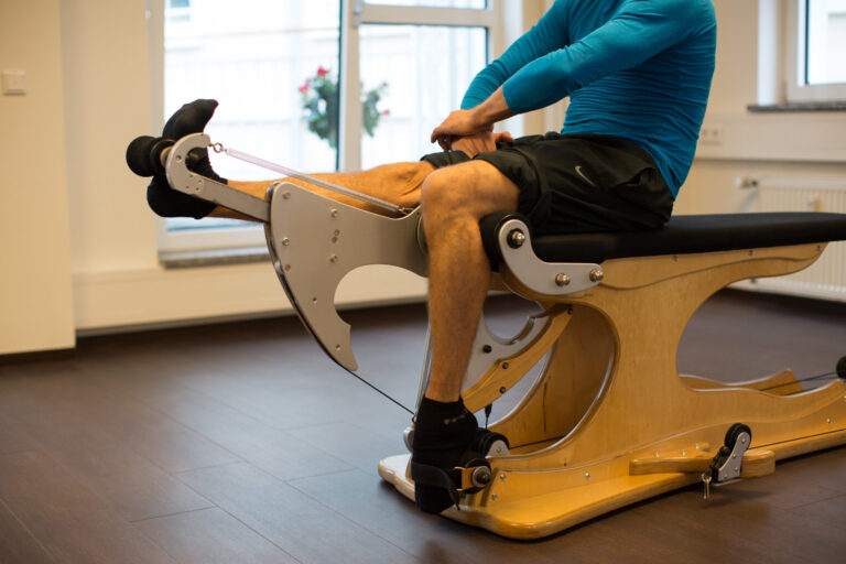 Mann trainiert die Beine an einem Gyrotonic-Gerät im Studio.