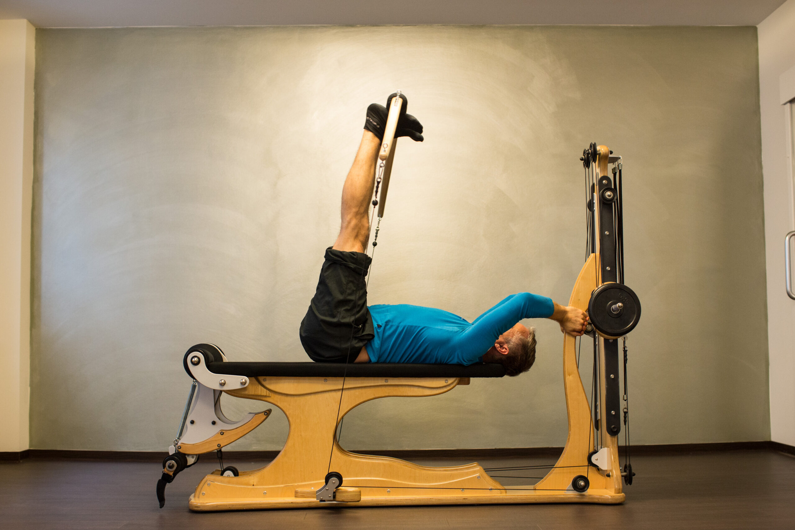 Mann trainiert Beine und Rumpf an der Gyrotonic Leg Extension Unit, Beine gestreckt in der Luft